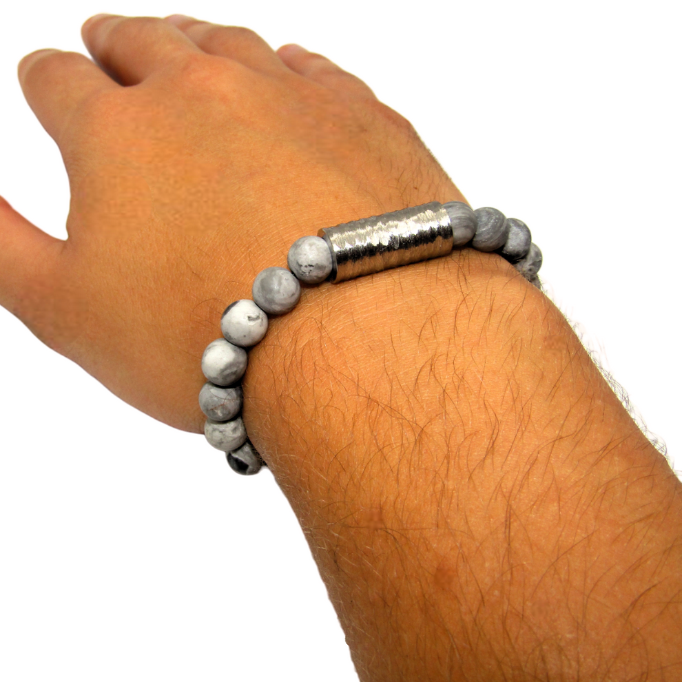 L'image représente le bracelet élastique fait de jaspe et de perles tube en acier inoxydable. Il est élégant et durable, parfait pour les hommes qui recherchent un look original et sophistiqué. Sa longueur de 20 cm, grâce à son élasticité, s'adaptera parfaitement à votre poignet.